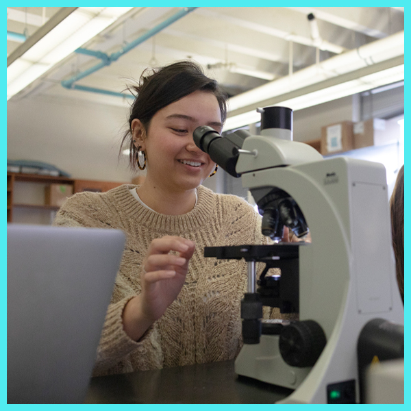 A student looks through microscope.
