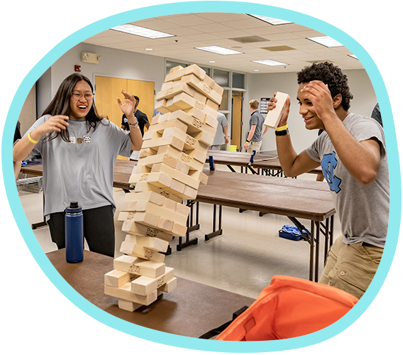 Jenga tower falling on table while two students laugh in student union